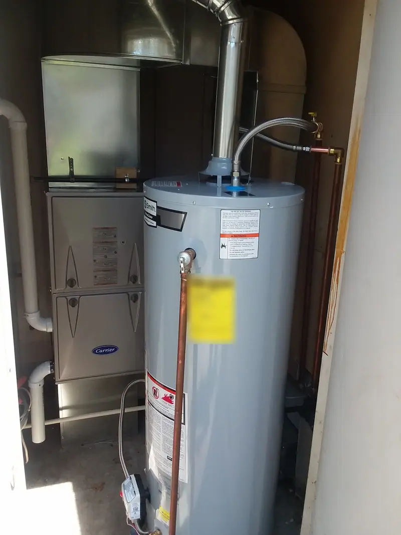 A Carrier gas furnace and a new water heater installed side by side in a utility closet
