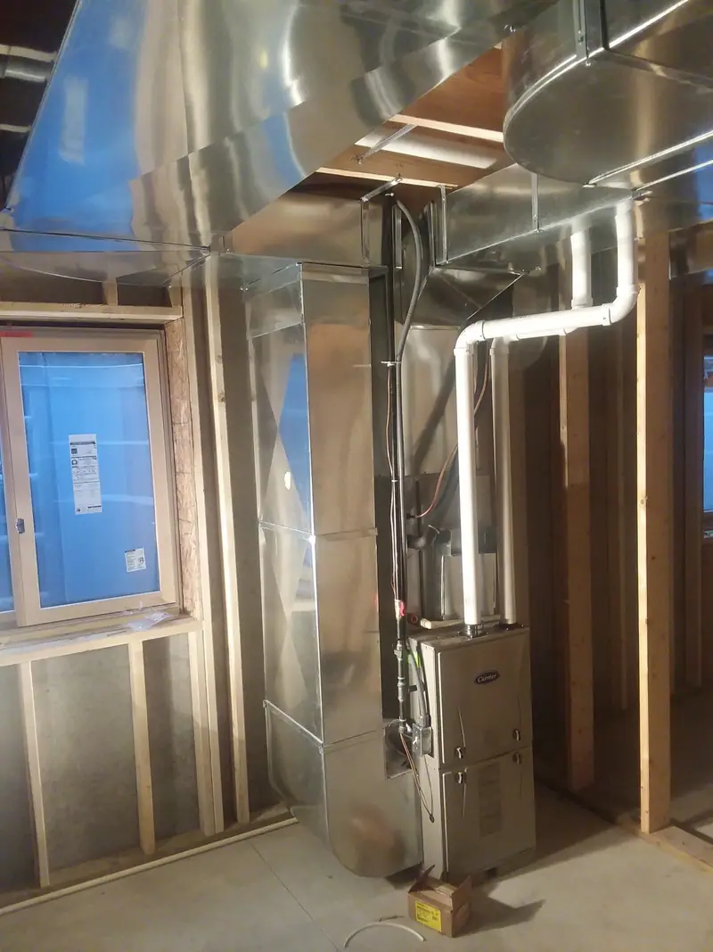 A new Carrier furnace with fresh sheet metal trunk lines in an unfinished new construction basement